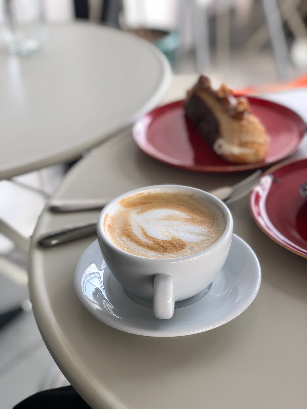 white ceramic mug with coffee on white ceramic saucer